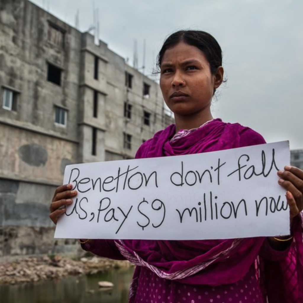 Protester calling out complicity of Western brands like Benetton, Matalan, Mango, Primark, Gucci, Versace, Mon Cler, Zara and Walmart, in the fatal Bangladesh Rana Plaza factory collapse, where 1134 people died.